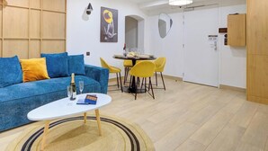 A modern living room with a blue sofa, a small white table, and yellow chairs.