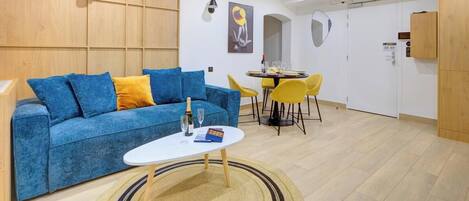 A modern living room with a blue sofa, a small white table, and yellow chairs.