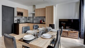 A modern kitchen with wooden cabinets, a tiled backsplash, and a dining area with a wooden table set for six. - TBS 161 - Spacious apartment in the heart of Paris (Paris)