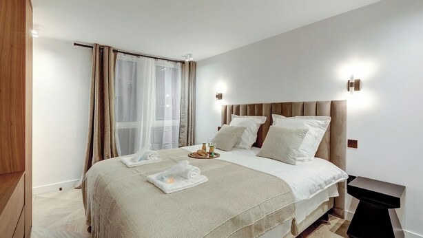 Un dormitorio moderno con una cama grande, una mesita de noche, un armario y una ventana con cortinas.