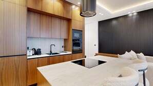 Una cocina moderna con armarios de madera, horno empotrado y una isla grande con fregadero.