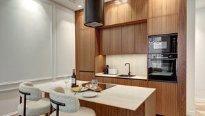 Una cocina moderna con armarios de madera, horno empotrado y comedor con mesa y sillas.