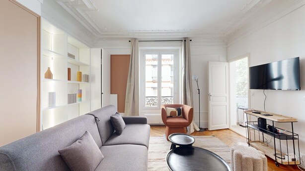 A modern living room with a grey sofa, a brown armchair, a flat-screen TV, and a bookshelf. - TBS 285 - Elegant and modern apartment in Paris (Paris)
