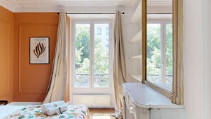 A hotel room with a bed, a dresser, and a window with curtains. - TBS 285 - Elegant and modern apartment in Paris (Paris)
