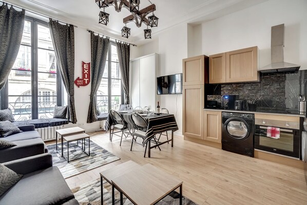 A modern apartment with a dining area, sofa, kitchen, and laundry facilities.