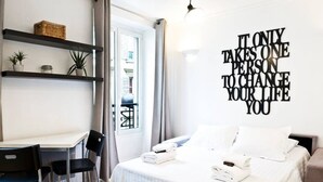 A hotel room with a bed, a desk, and a wall with motivational text. - TBS 274 - Lovely apartment near Sacré-Coeur (Paris)