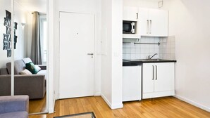 A compact kitchen with white cabinets, a microwave, and a sink. - TBS 274 - Lovely apartment near Sacré-Coeur (Paris)