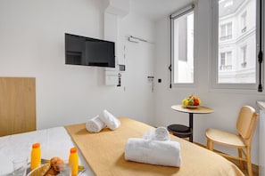 Relax in a serene space with a neatly made bed, flat-screen TV, and comfortable chair.