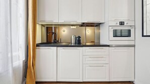 Una cocina moderna con armarios blancos, horno integrado y campana extractora de acero inoxidable.
