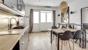 Eine moderne Küche mit Essbereich, ausgestattet mit einem großen Fenster, einer Hängeleuchte und einem minimalistischen Design.