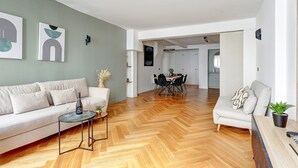 Een moderne woonkamer met een bank, een salontafel en een eethoek met een tafel en stoelen.