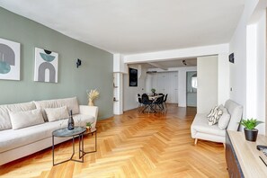 Relax in this stylish living space with a sofa set against a vibrant wall, abstract artwork, and a dining area.