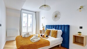Een moderne slaapkamer met een groot bed, een blauw hoofdeinde en een houten vloer.