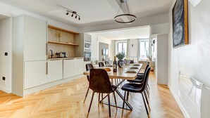 Een moderne keuken met witte kastjes, een houten eettafel en zwarte stoelen.