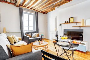 Un soggiorno moderno con un divano, un tavolo da pranzo con sedie, una televisione e una finestra con tende.