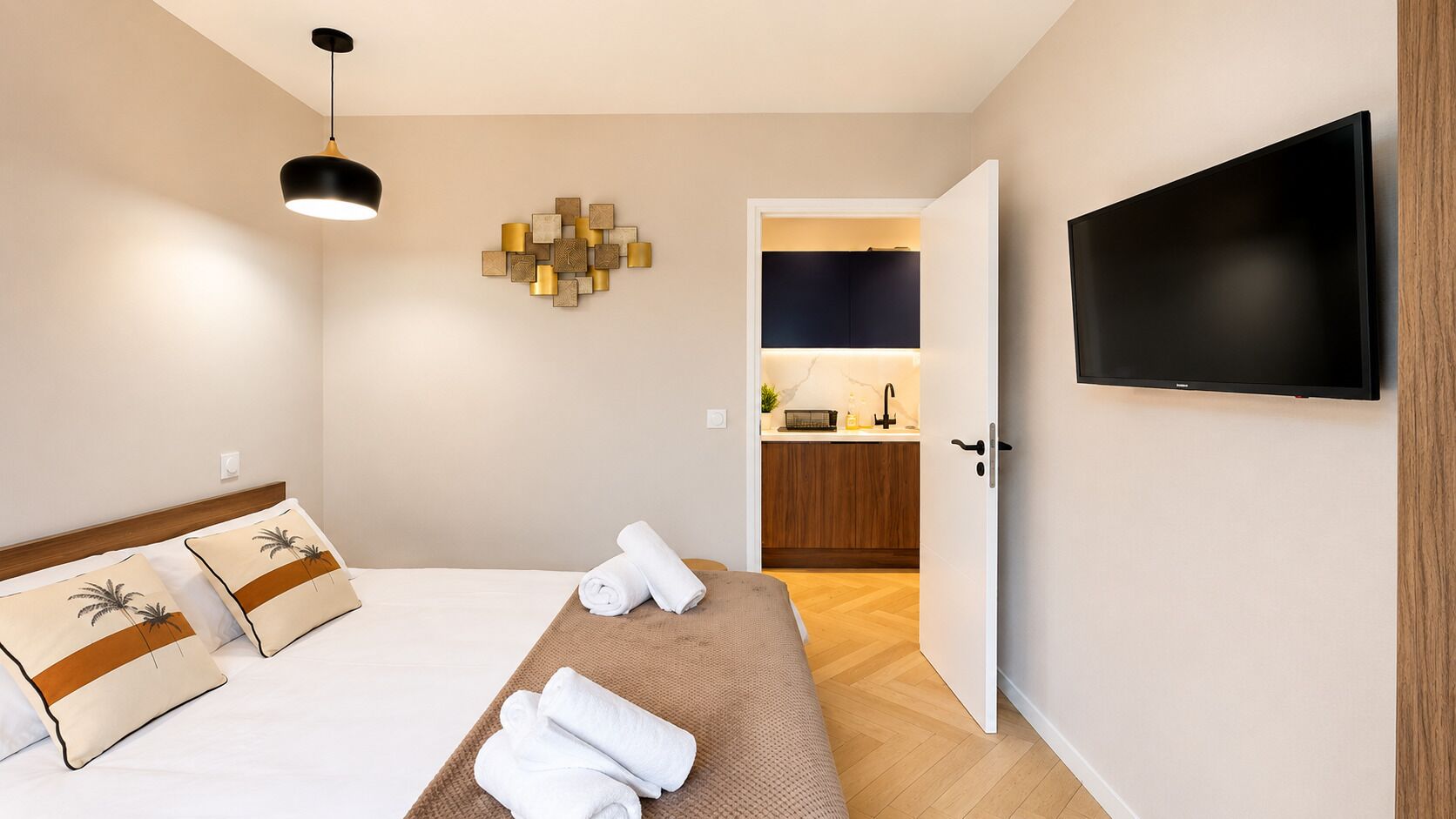 Ett hotellrum med en säng, en platt-TV, ett konstverk på väggen och ett litet pentry i bakgrunden.