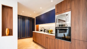 Una cocina moderna con armarios de madera, horno empotrado y una encimera con frutero.