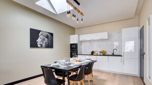 A modern kitchen with white cabinets, a dining table set with chairs, and a black and white photograph on the wall. - TBS 60 - Spacious and elegant apartment (Paris)