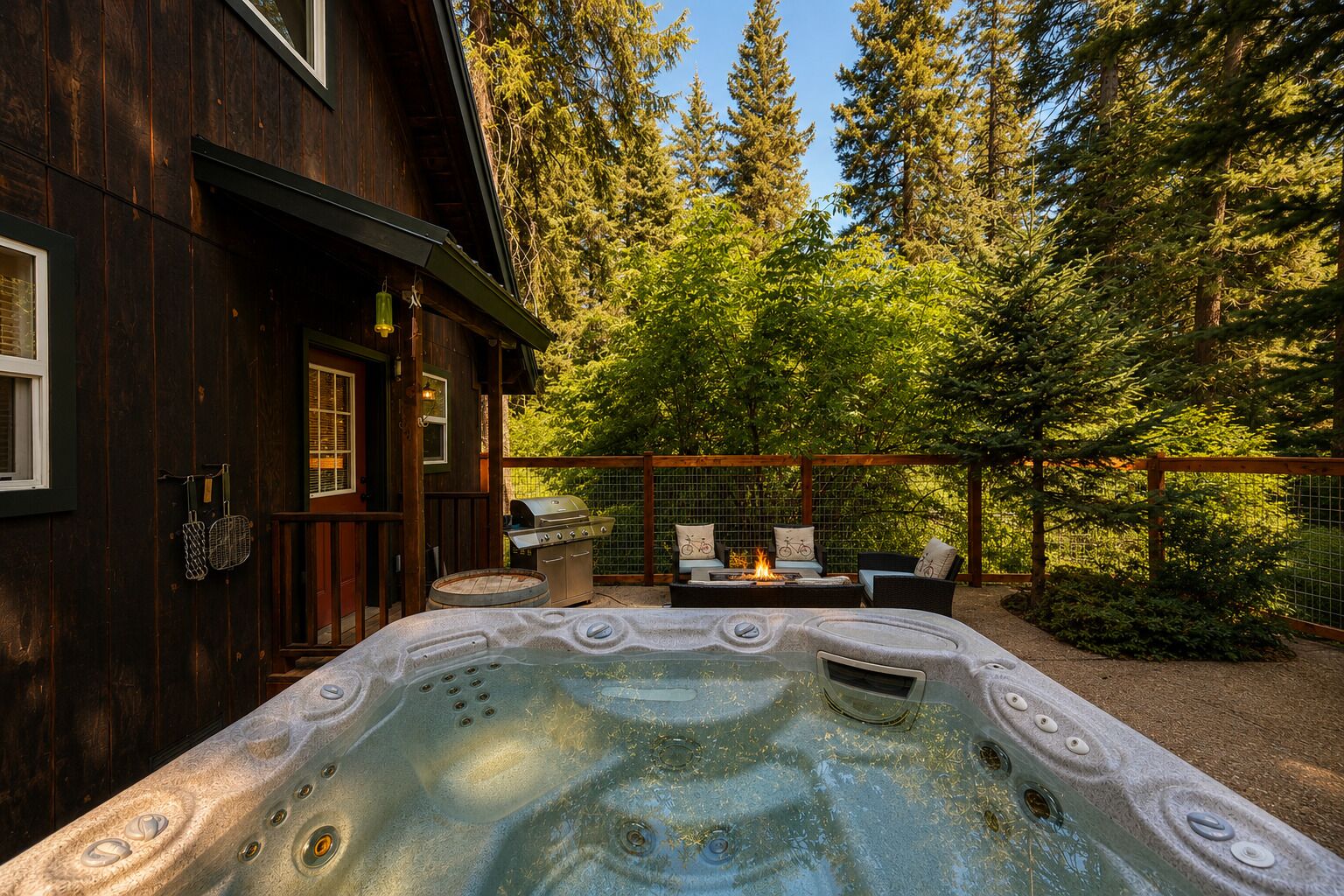 Une cabane en bois dotée d’un bain à remous, d’un espace extérieur aménagé et offrant une vue sur une forêt.