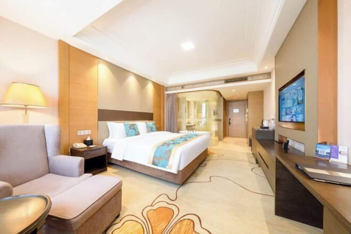 Une chambre d’hôtel avec un lit, un bureau, une chaise, une télévision et une lampe.