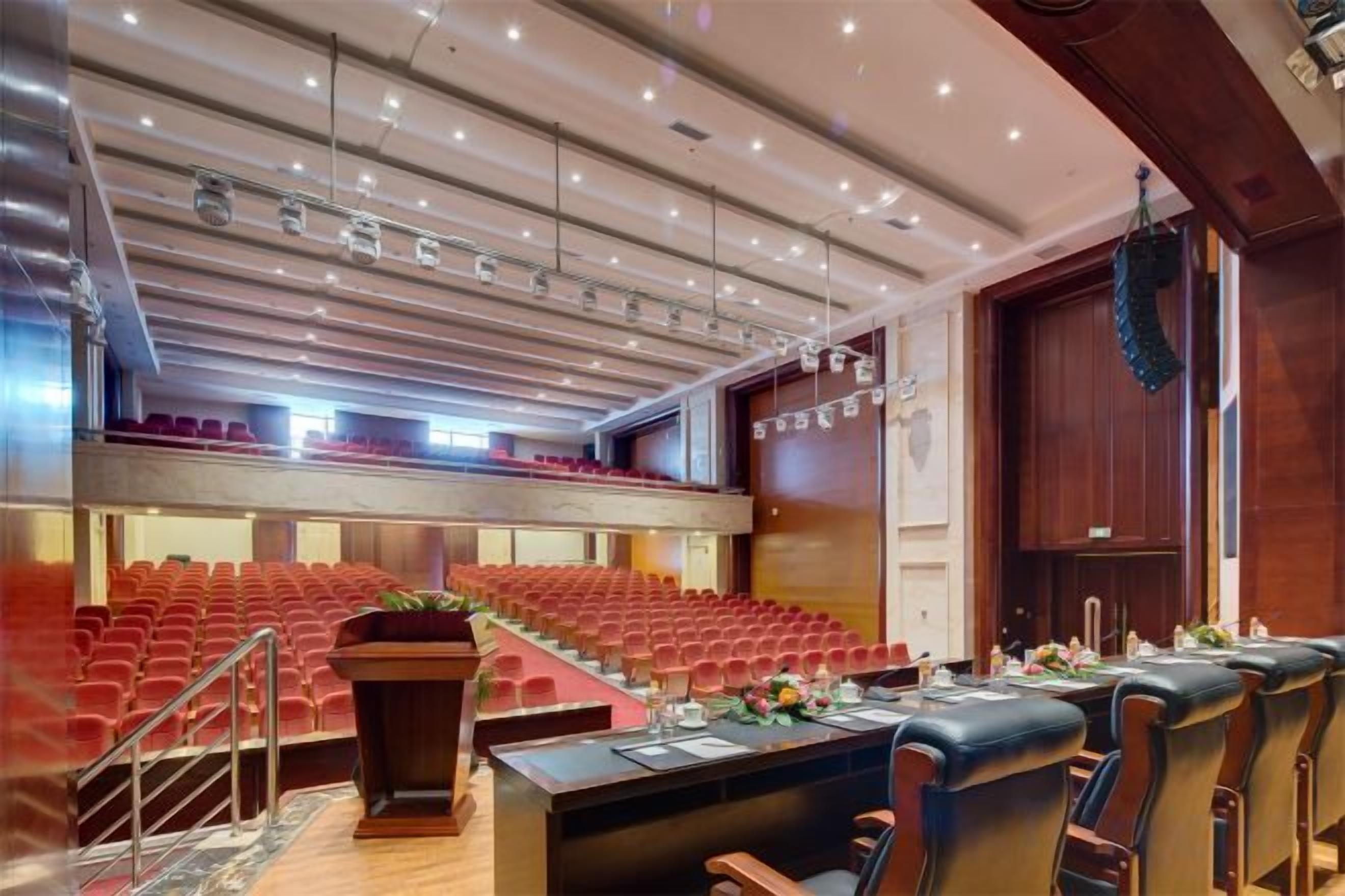 A conference room with tiered seating, a long table with chairs, and a stage area.
