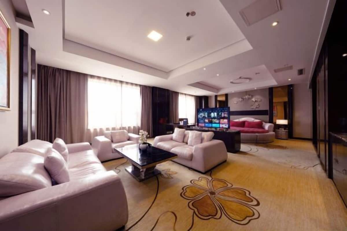 Une chambre d’hôtel moderne dotée d’un espace salon comprenant un canapé, une table basse et un téléviseur à écran plat.