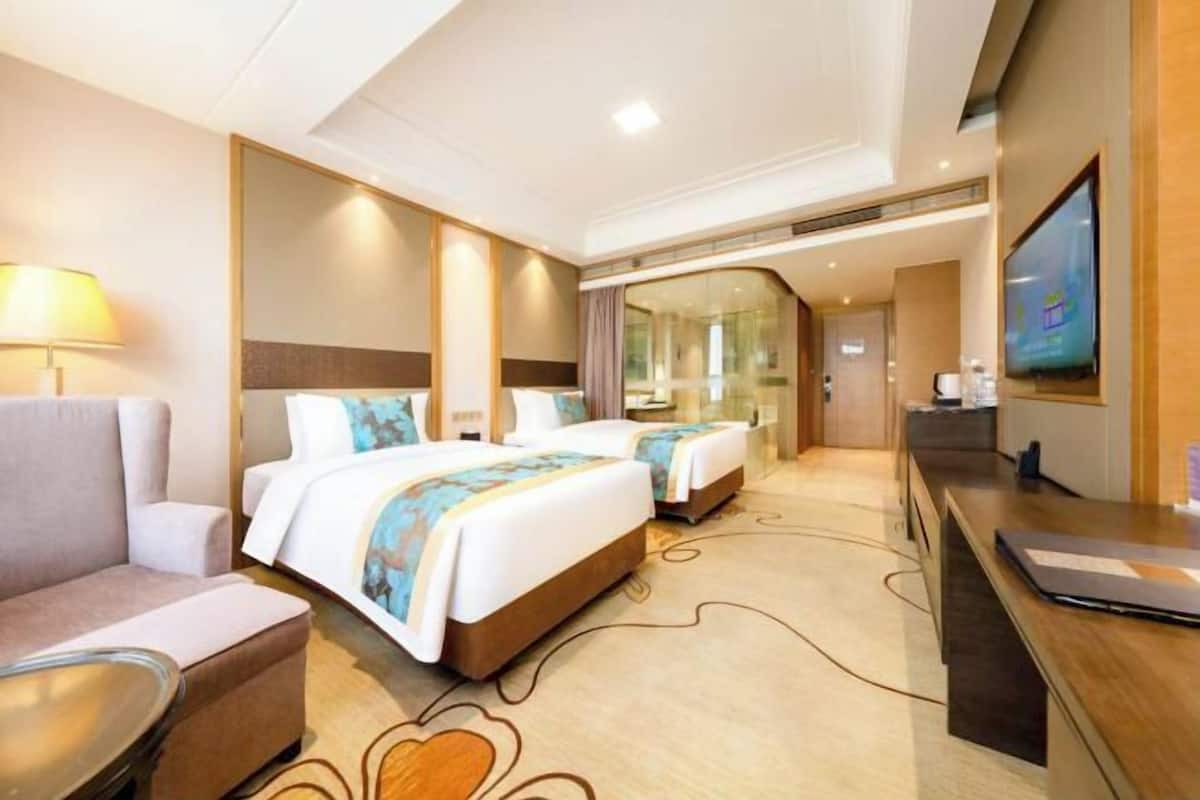 Une chambre d’hôtel avec deux lits, un canapé, un bureau, une télévision et un miroir.