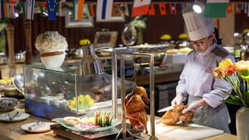 A chef preparing food in a kitchen with various flags and a display case with food items.