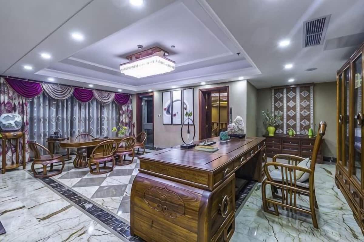 A dining area with a marble floor, wooden furniture, and a chandelier.