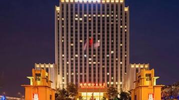A high-rise building with a prominent entrance and illuminated signage.