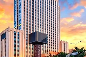 Ein hoch aufragendes Gebäude mit modernem Design, das einen markanten, zentralen Turm und zahlreiche Fenster aufweist.