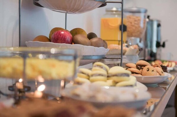 A buffet with various food items including fruits, pastries, and a beverage dispenser. - HOTEL DEL VIEJO ESQUIADOR (San Martín de los Andes)