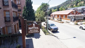 Entrada de un hotel con un cartel, una carretera y un edificio al fondo.