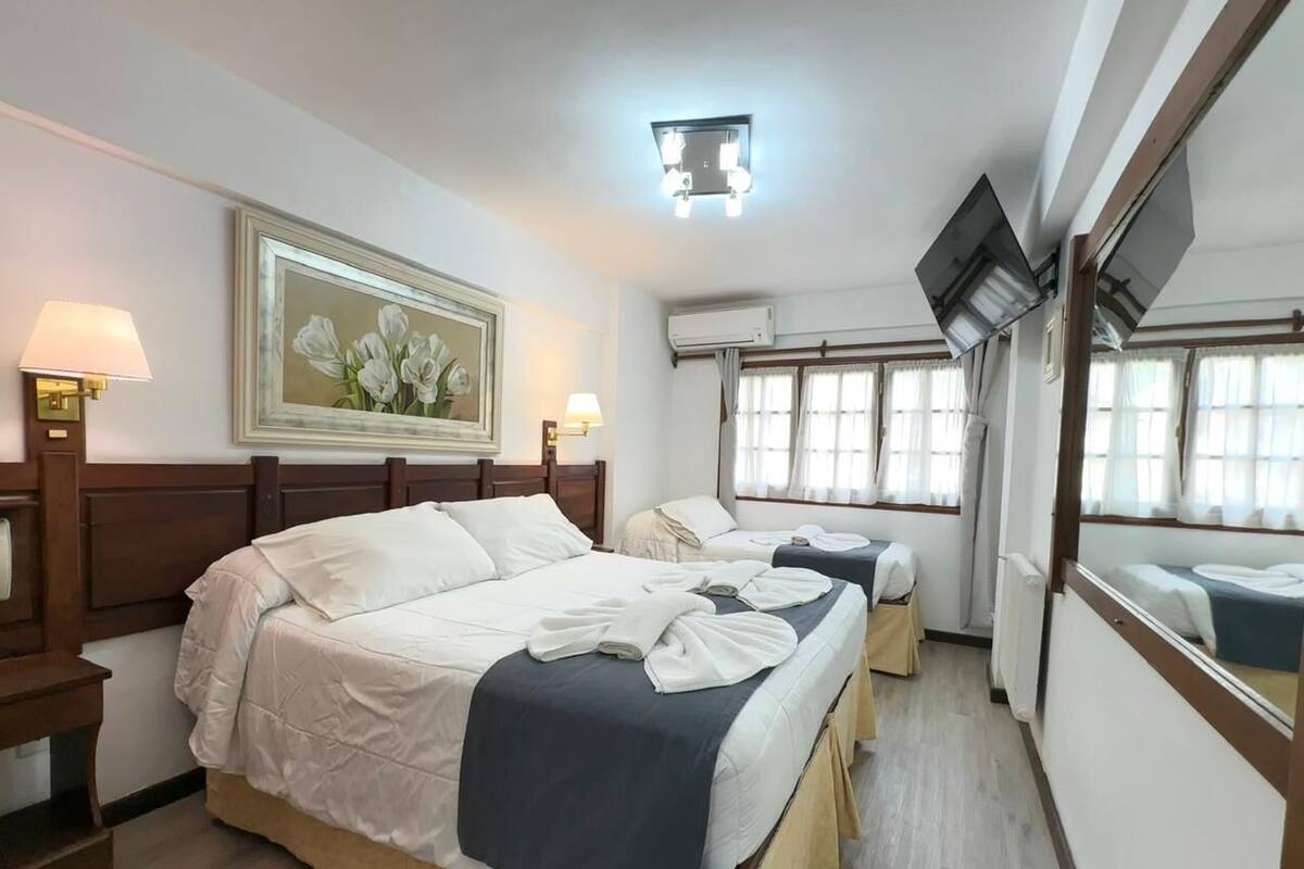 A hotel room with two beds, a painting on the wall, and an air conditioning unit.