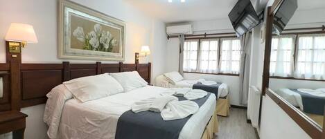 A hotel room with two beds, a painting on the wall, and an air conditioning unit.