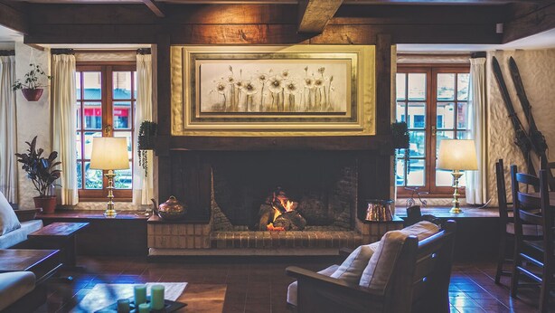 Una sala de estar acogedora con chimenea, asientos cómodos y una obra de arte grande enmarcada sobre la repisa.