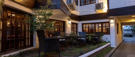 Un patio con mobiliario exterior, una planta en maceta y un vehículo al fondo.