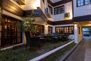 A courtyard with outdoor seating, a potted plant, and a vehicle in the background.