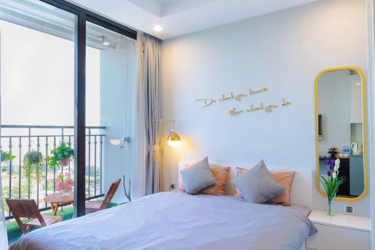 Un dormitorio con cama, mesita de noche, espejo y balcón con vistas.