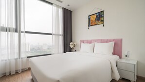 A hotel room with a large bed, a nightstand, a painting on the wall, and a view of the city through the window.
