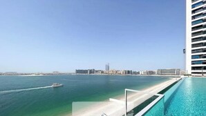 Um hotel moderno com piscina, vista para a praia e horizonte urbano.