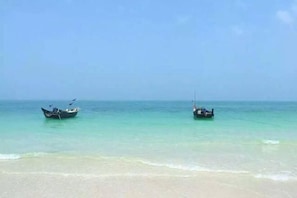 A beach with two boats anchored in calm waters. - Weizhou Island Sea and Tianzhilian Wangxi Inn (Dishui Danping Branch) (Beihai)