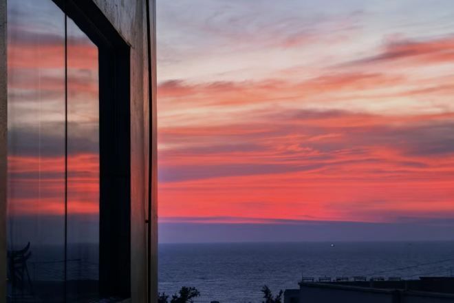 A sunset view from a balcony with a clear sky and ocean in the background.