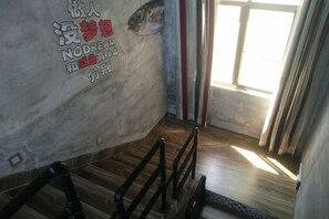 Una habitación con piso de madera, una ventana con cortinas y una pared con una ilustración de un pez y texto.