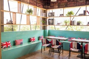 Un restaurante con pared verde, estantes de madera y mesas adornadas con banderas rojas y blancas.