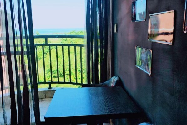 A balcony with a table and chairs, a view of greenery, and several framed pictures on the wall. - Weizhou Island Sea and Tianzhilian Wangxi Inn (Dishui Danping Branch) (Beihai)