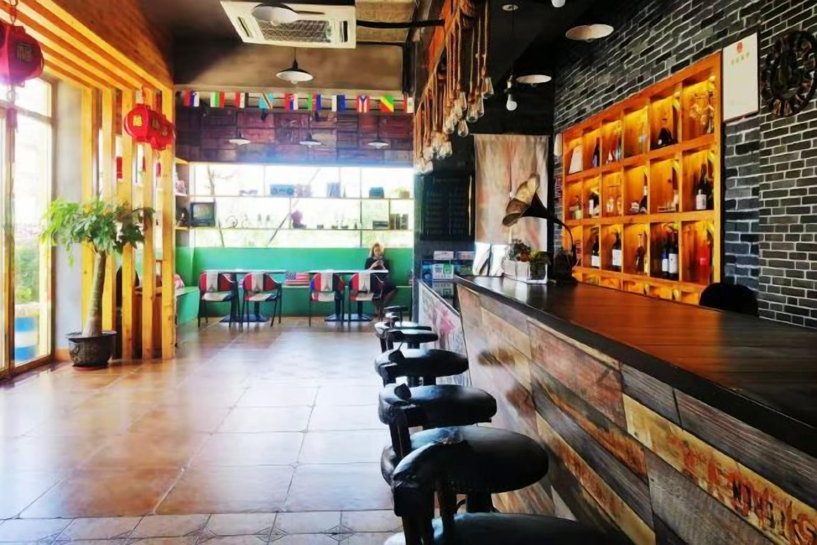A bar area with stools, a counter, and shelves with bottles.