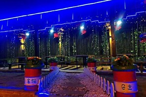 A nighttime outdoor area with vertical light strips, potted plants, and a paved walkway. - Weizhou Island Sea and Tianzhilian Wangxi Inn (Dishui Danping Branch) (Beihai)