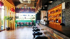 A restaurant with a long counter, bar stools, and a brick wall with shelves of bottles. - Weizhou Island Sea and Tianzhilian Wangxi Inn (Dishui Danping Branch) (Beihai)