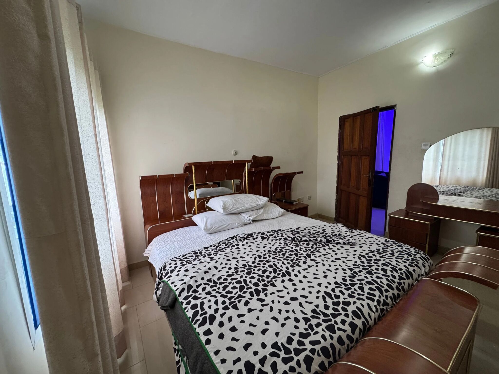 A bedroom with a bed, a desk, and a wardrobe.